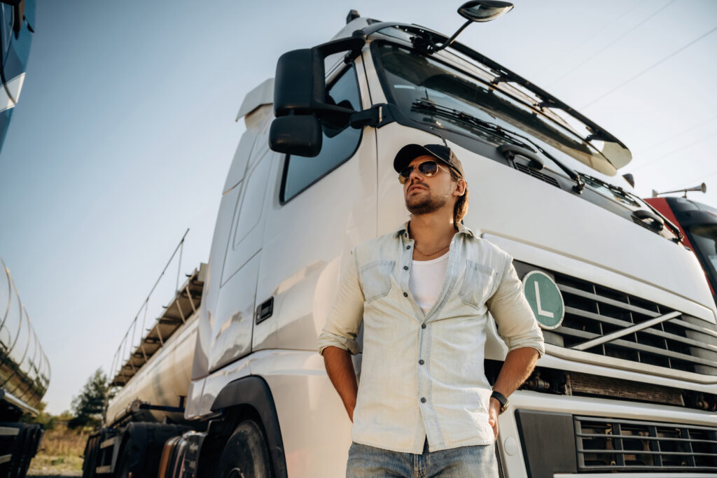 View from below, standing and posing. Truck driver is near the transport outdoors